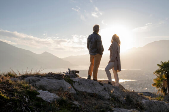 Mature couple hike along sunny mountain ridge, sunset